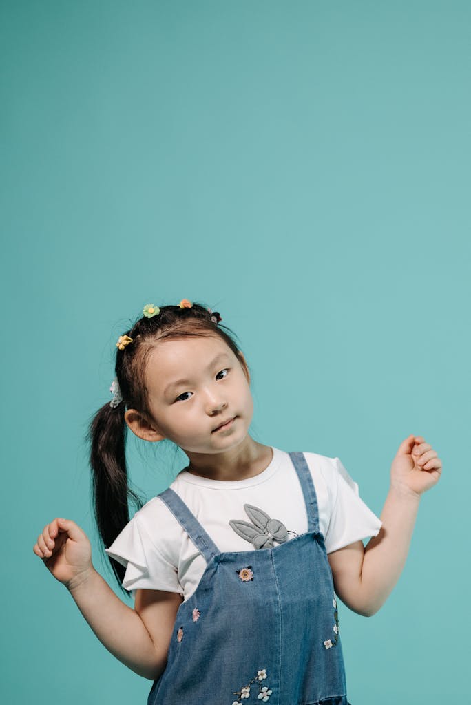 Photo by Pavel Danilyuk Cute Asian girl striking a pose in denim against a turquoise background.