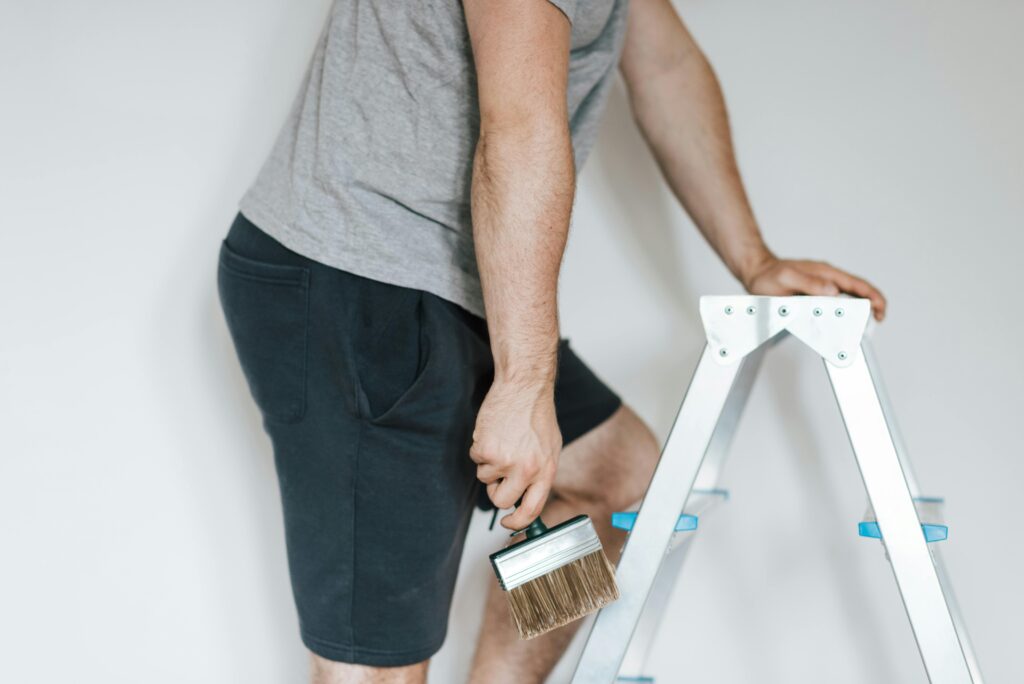 pexels-photo-4792500-4792500 Side view of crop anonymous male decorator in casual clothes preparing to painting walls of light room while standing on stepladder