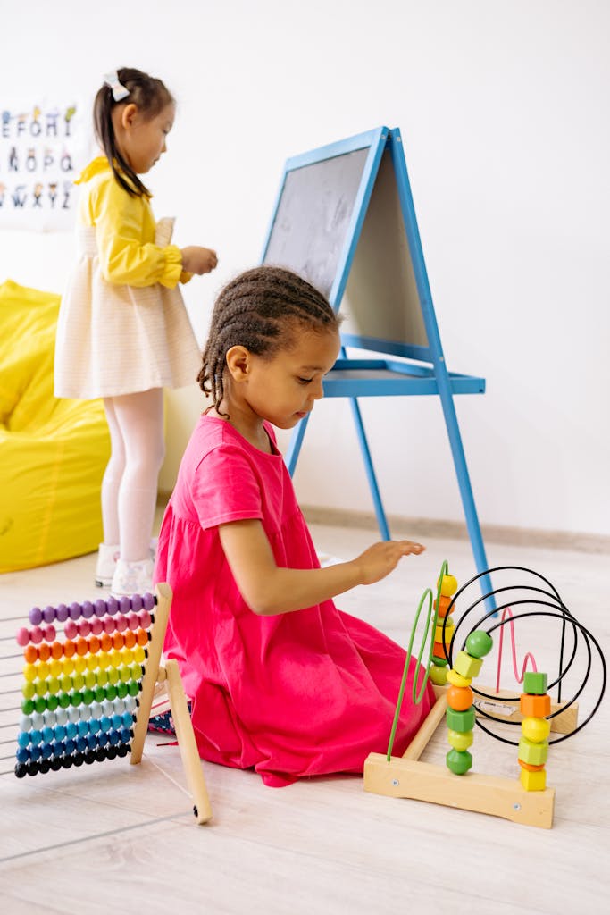 Photo by Yan Krukau Two girls engaging in playful learning with abacus and toys in a bright classroom.